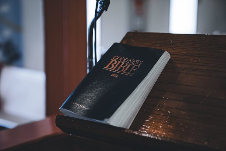 Close-up of the Good News Bible resting on a wooden lectern, ideal for religious themes.